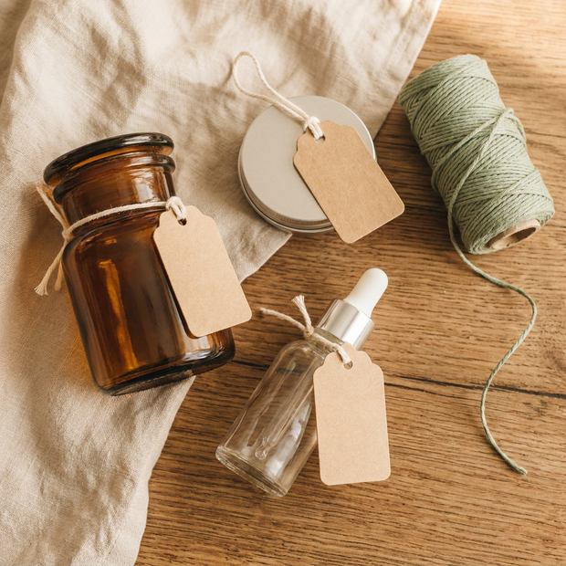 Nachhaltige DIY-Kosmetikverpackung - Glasdöschen Braunglasflasche Kraftpapier-Etiketten auf natürlichem Leinen