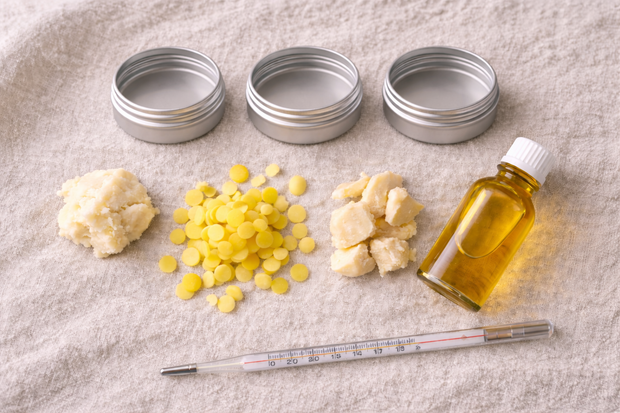 Natürliche DIY-Kosmetik-Einstiegszutaten - Sheabutter, Kakaobutter, Bienenwachs und Trägeröl auf einer Holzfläche │