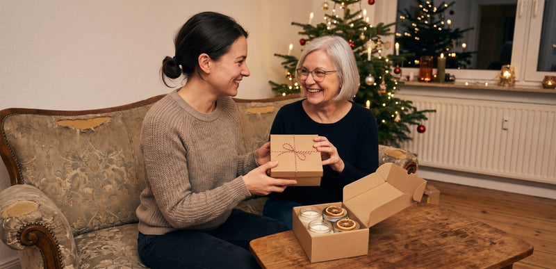 Tochter überreicht ihrer Mutter zu Weihnachten selbstgemachte Kerzen und Balsamdosen