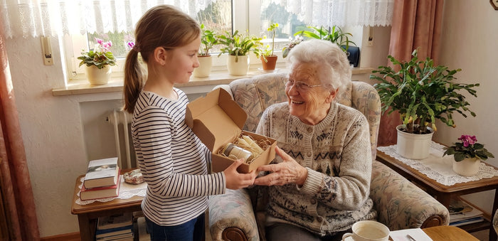 Enkelin schenkt ihrer Großmutter eine selbstgemachte Kerze und Körperbutter