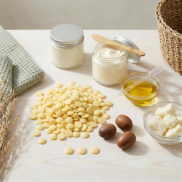 Body Butter Kern Set, zweite Ansicht: Kakaobutter-Pastillen, offene Sheabutter-Dose, Mandelöl und die fertige Körperbutter in eigenen Gläsern