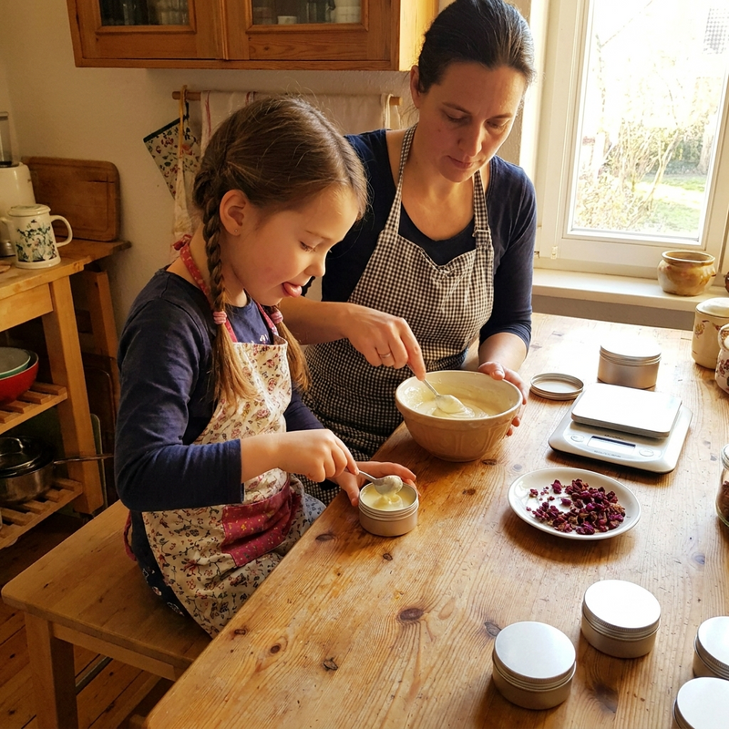 Mutter und Tochter füllen gemeinsam Balsam in kleine Dosen